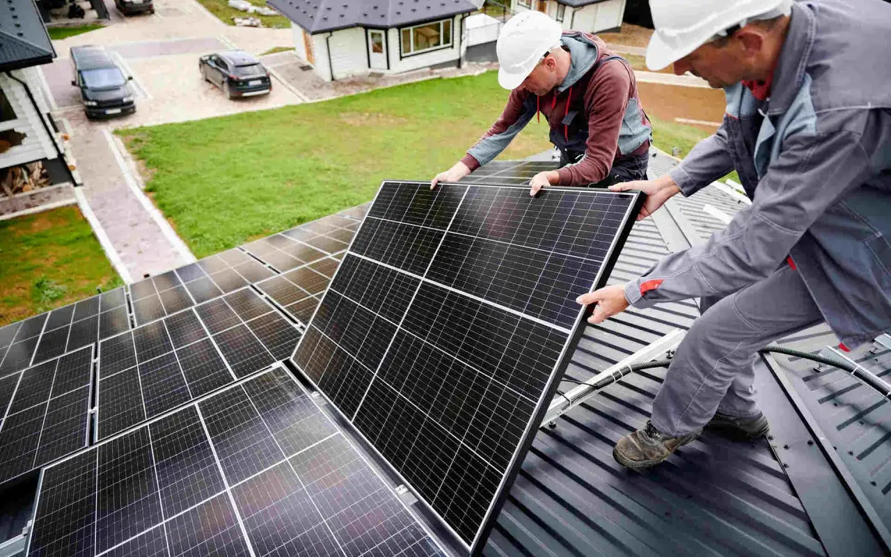 Dwóch elektryków montuje panele słoneczne. Zastanawiasz się, ile zarabia elektryk na godzinę?