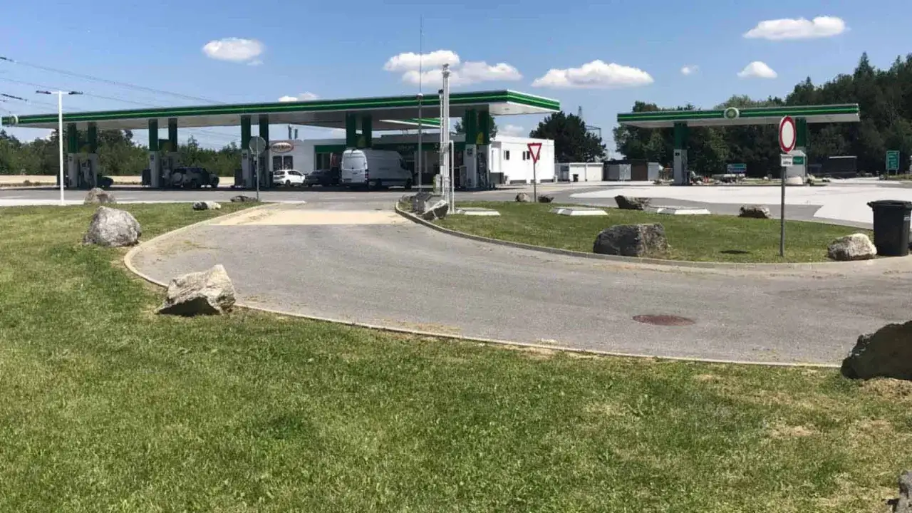 Station-service BP sur l'aire autoroute A9. Des voitures et un van sont stationn&eacute;s sous les pompes. Le ciel est bleu avec quelques nuages.