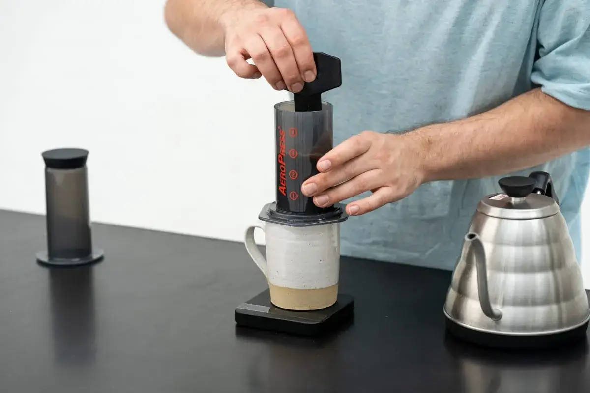 Przygotowanie aromatycznej kawy z AeroPress. Widać czajnik i akcesoria do parzenia.