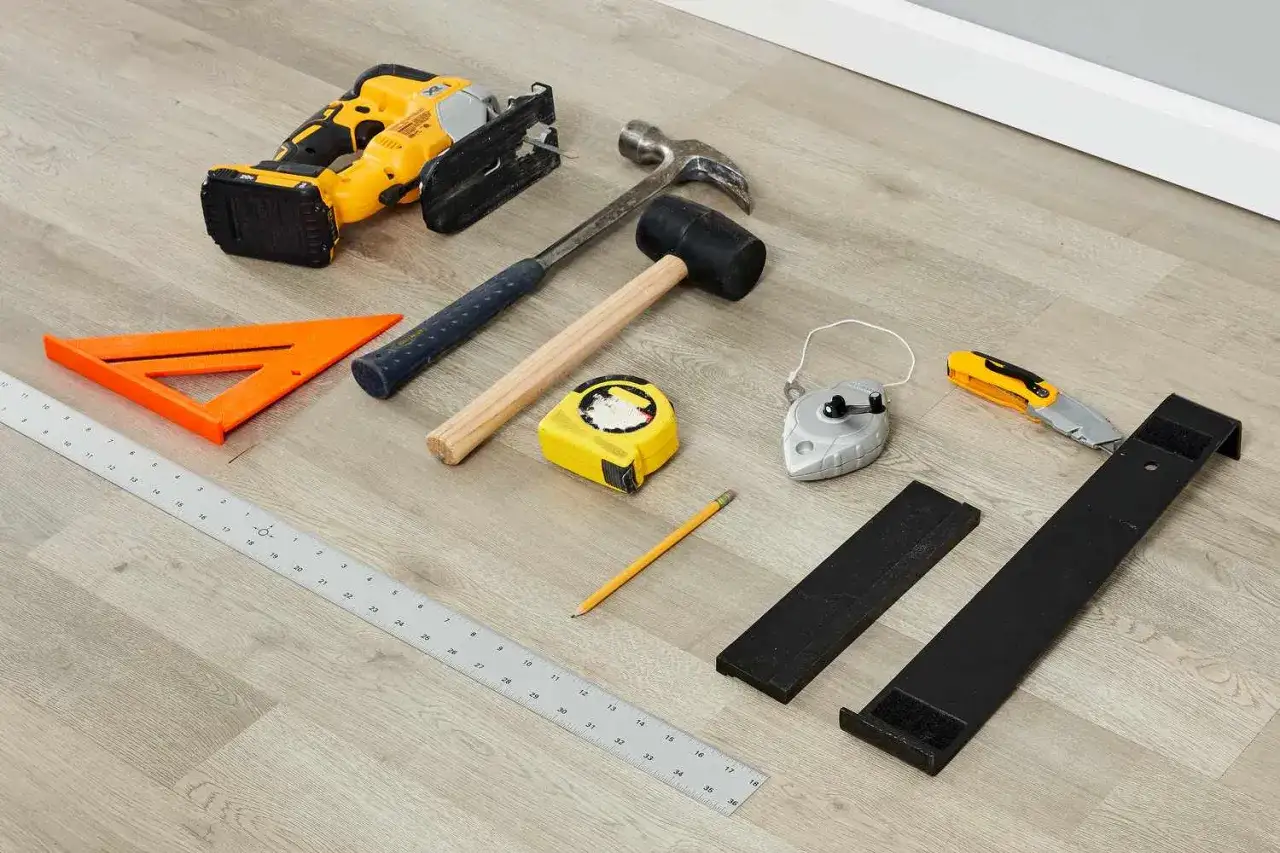 Herramientas para saber como poner suelo laminado: sierra de calar, martillos, cinta métrica, escuadra, lápiz, plomada, cúter y soportes.