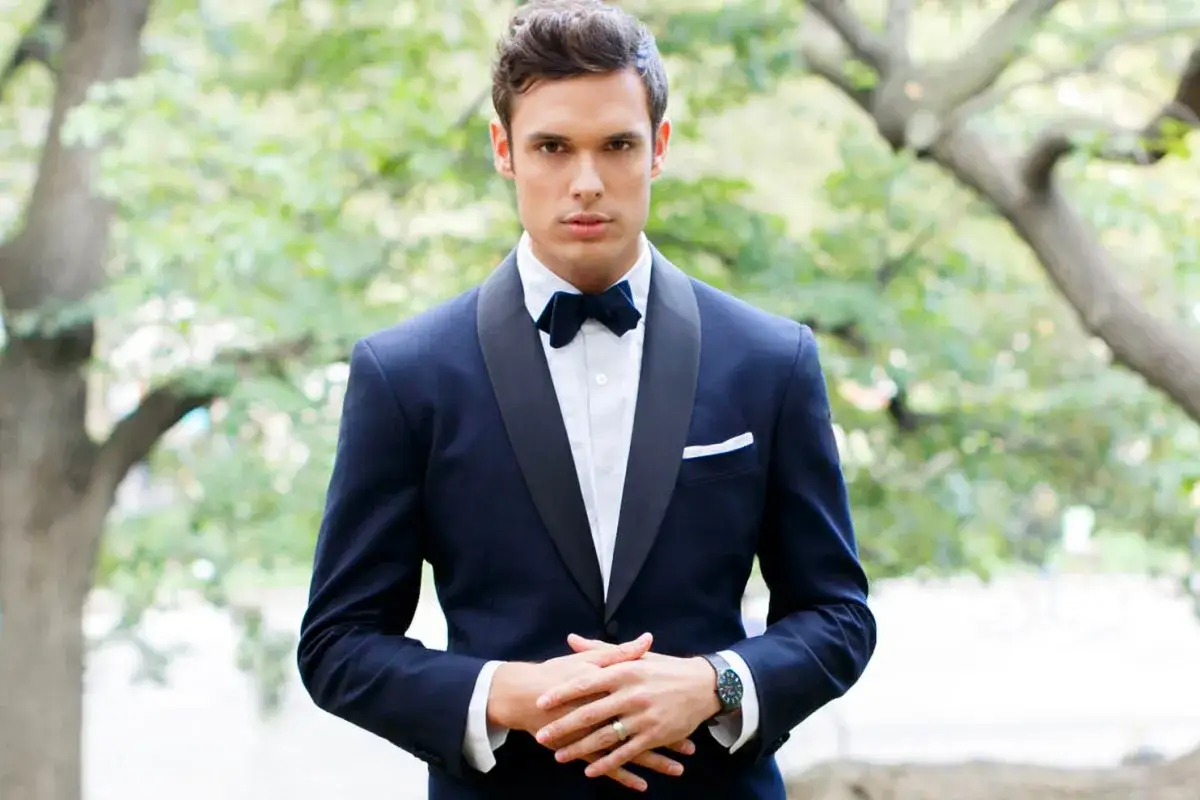 Un elegante sposo con smoking blu, pronto per il suo grande giorno. I suoi testimoni lo ammirano.