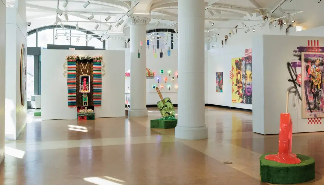 Vibrant art fills the Lanoue Gallery, featuring colorful paintings, a woven tapestry, and a melting popsicle sculpture.