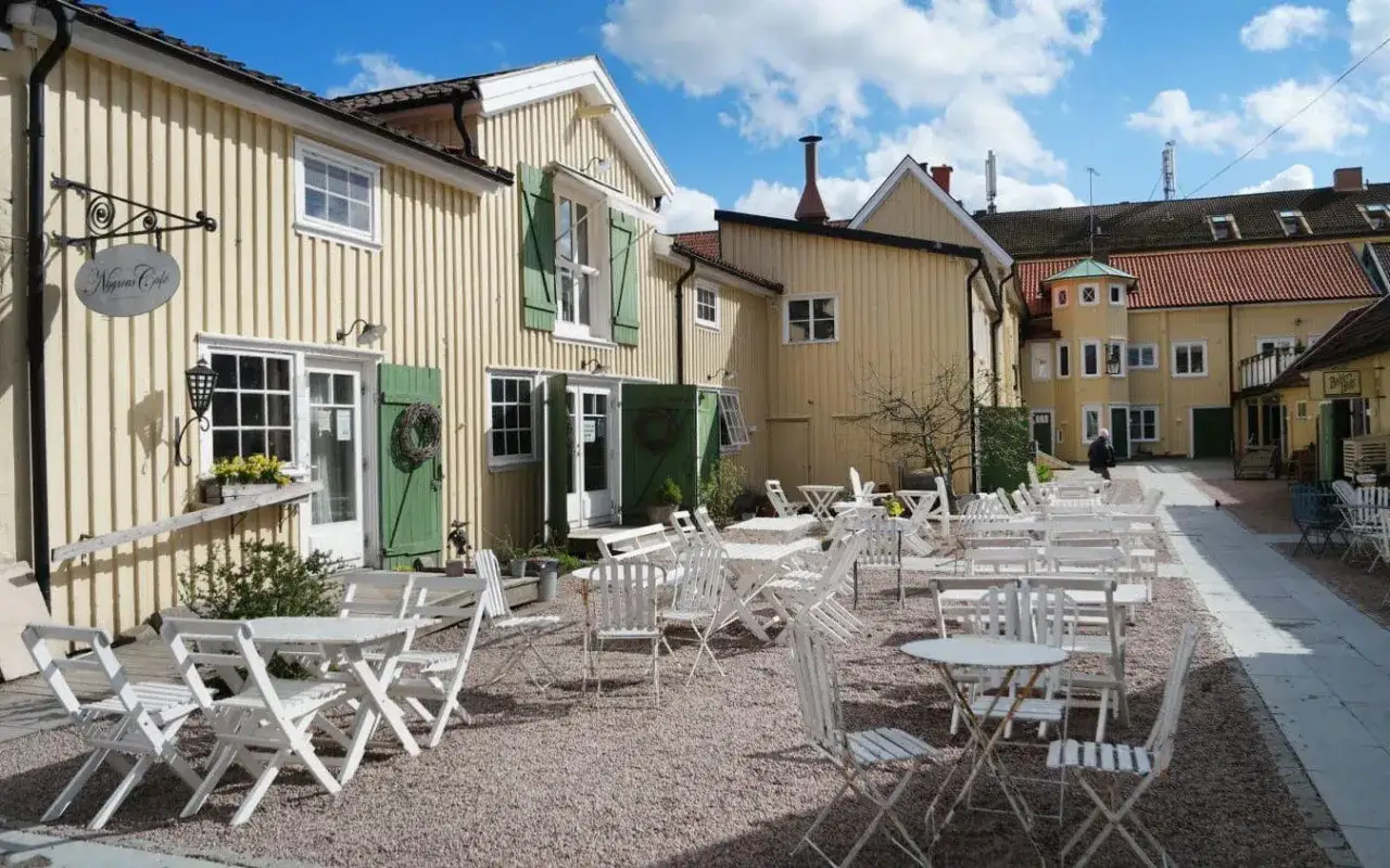 En charmig innergård med många vita utemöbler, perfekt för en fika. Nygrens Café bjuder in till en stunds avkoppling med en god kopp svenskt kaffe.