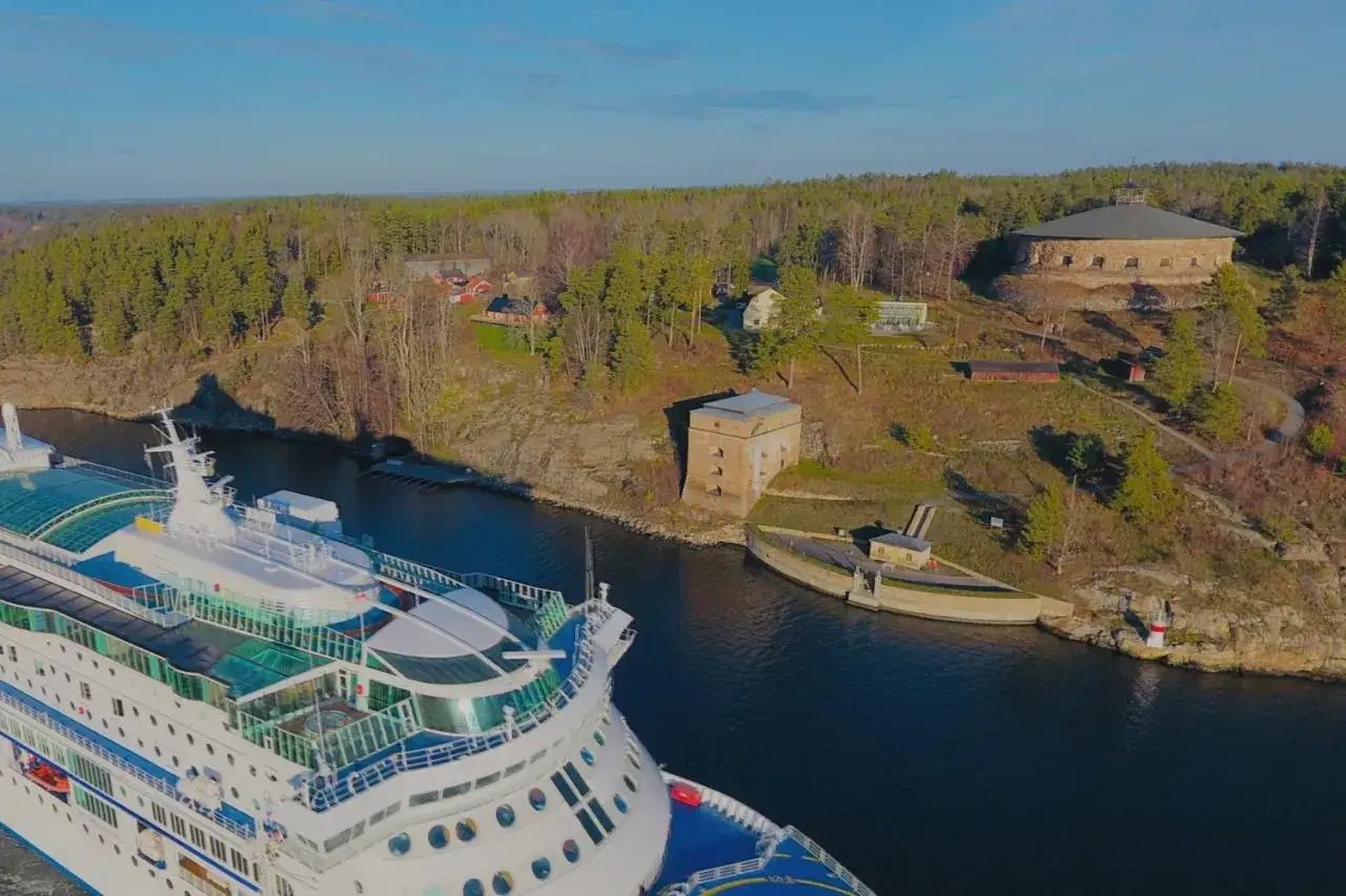 Kryssningsfartyg passerar Fredriksborgs hotell och fästning i en svensk skärgård.