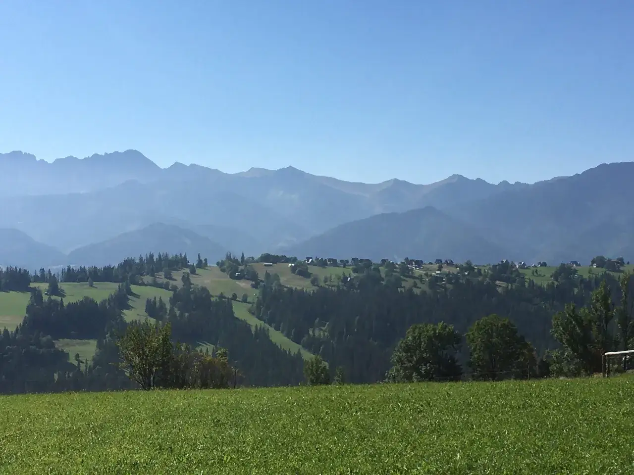 Zielony krajobraz z górami w tle. Widać pola, lasy i zabudowania. Idealna trasa nad Biały Dunajec.