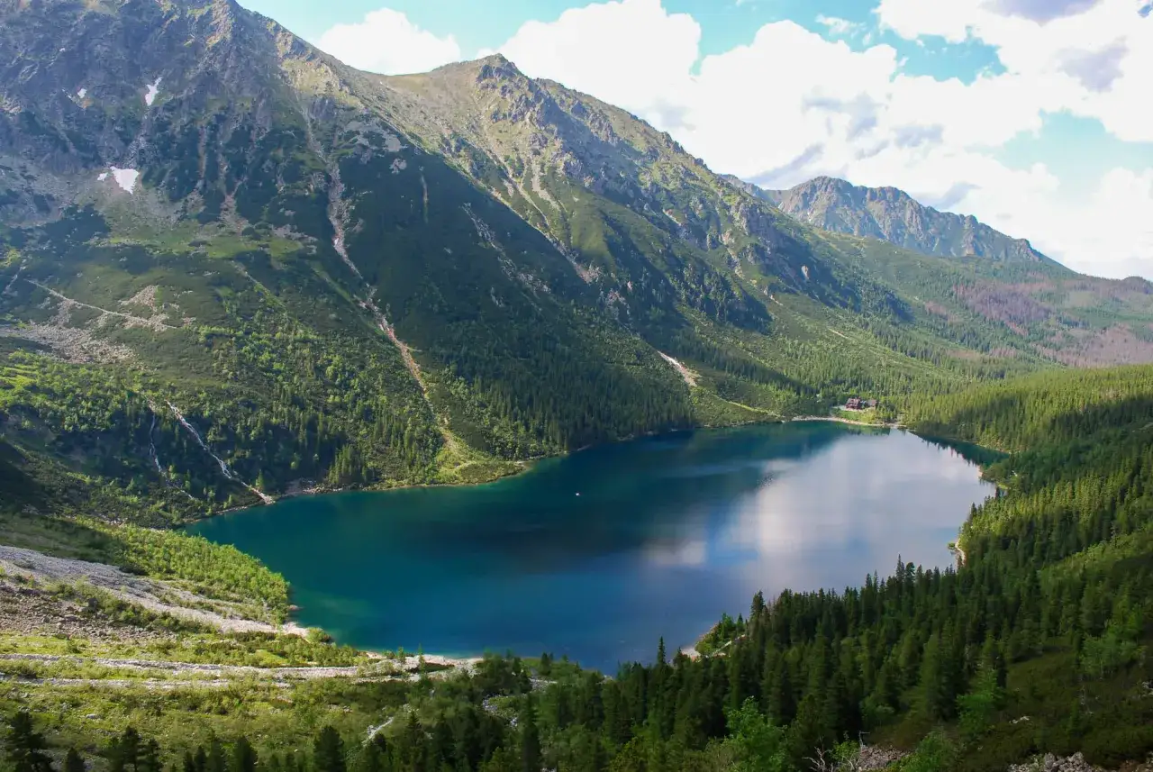 Widok na Morskie Oko, największe jezioro w Tatrach, otoczone stromymi, zalesionymi zboczami gór.