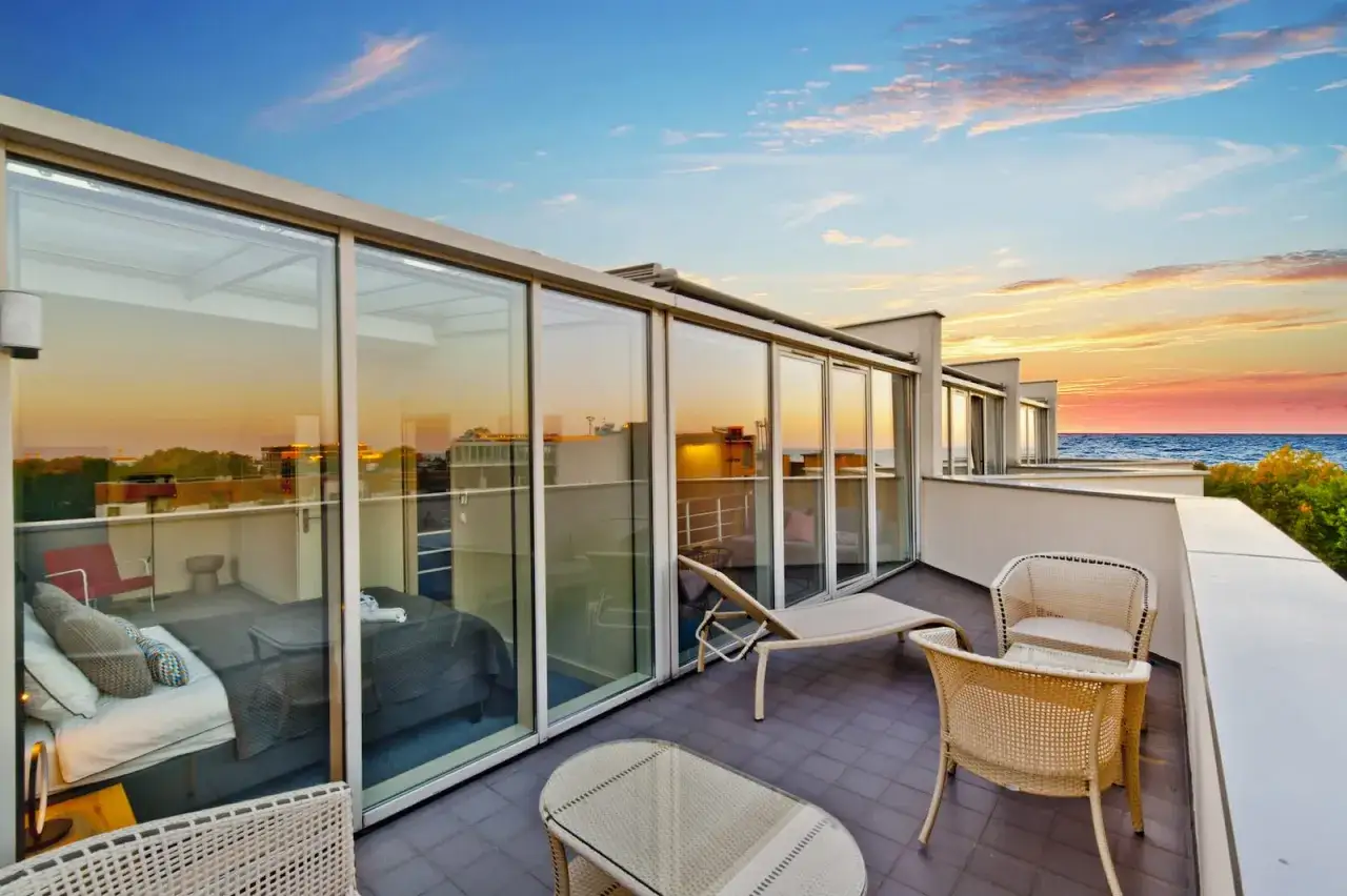 Władysławowo apartamenty przy plaży. Taras z widokiem na morze, meble wypoczynkowe i sypialnia z panoramicznymi oknami.