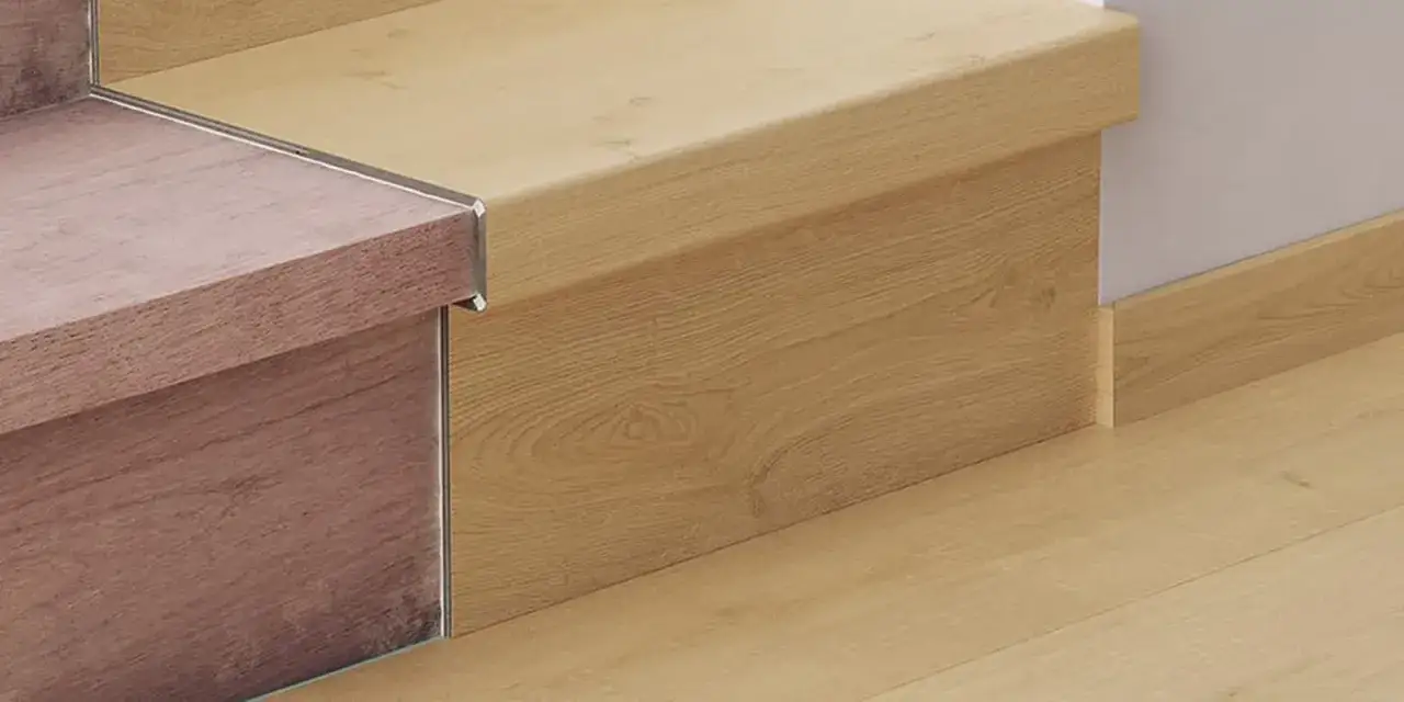 Detalle de escaleras con suelo laminado en tonos madera. Se aprecia el acabado de las huellas y contrahuellas, y el rodapi&eacute; a juego.
