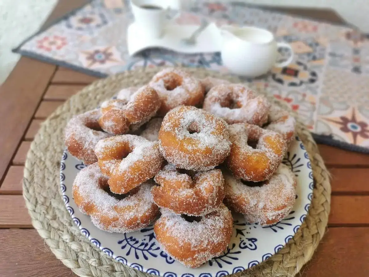 Un plato lleno de rosquillas caseras de toda la vida, espolvoreadas con az&uacute;car. Un placer para la vista y el paladar.