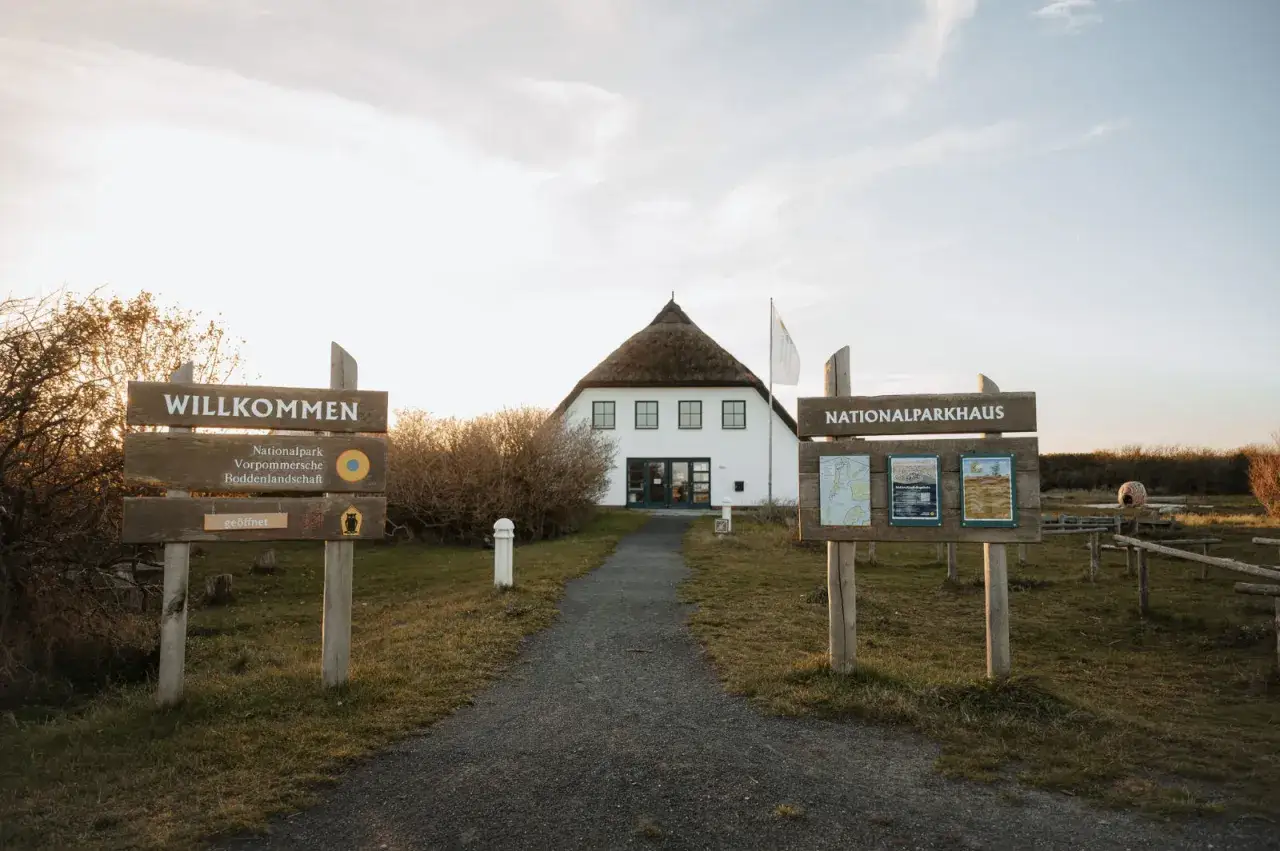 Willkommen am Nationalparkhaus in Hiddensee Vitte. Ein Weg führt zum Haus mit Reetdach.
