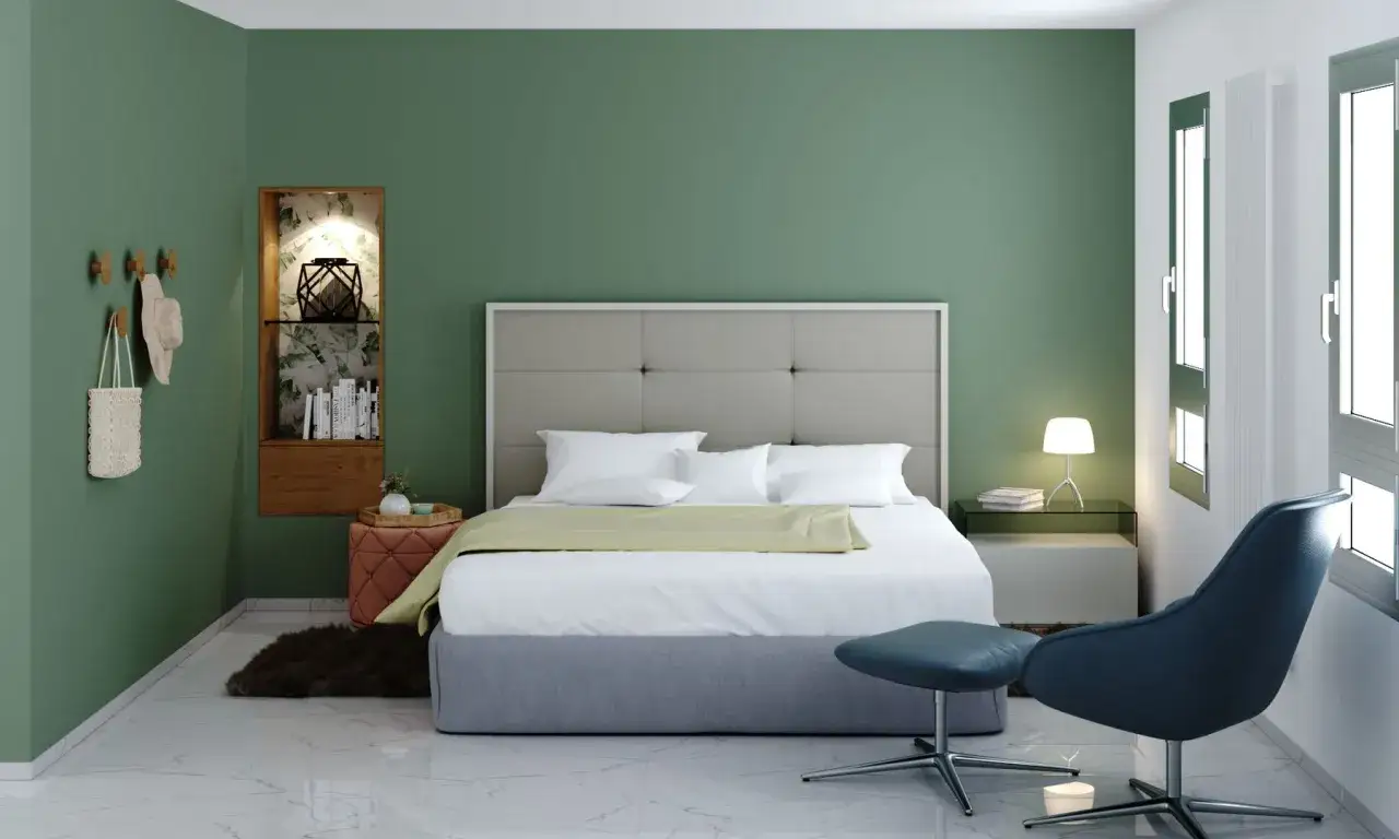 Dormitorio con paredes verde salvia, cama confortable y un sillón azul. Colores relajantes para dormitorios que invitan al descanso.