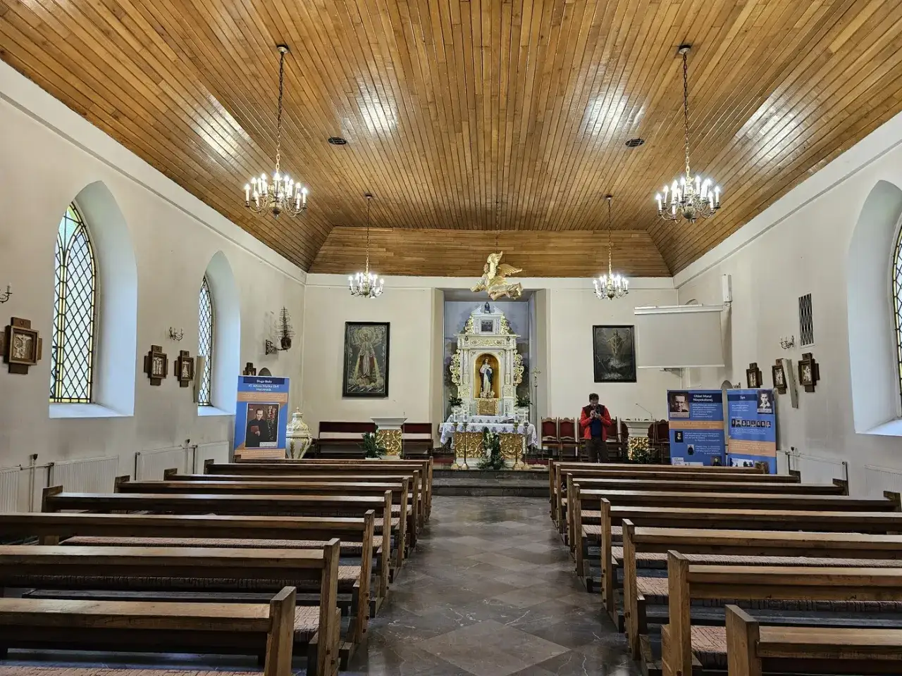 Wnętrze kościoła św. Jakuba w Łebie z drewnianym sufitem, ławkami i ołtarzem.