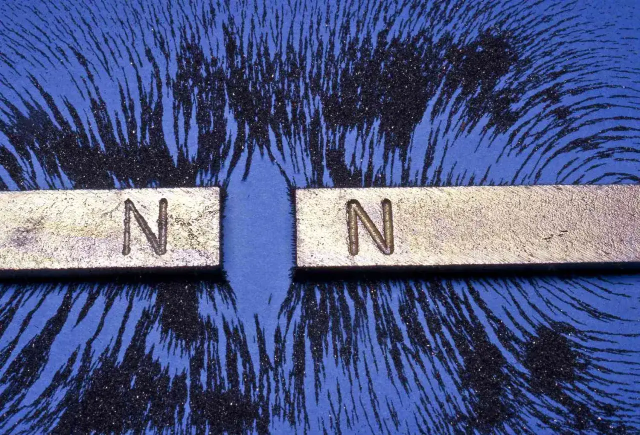 Zwei Nordpole von Stabmagneten stoßen sich ab. Eisenpulver zeigt die Magnetfeldlinien, ein klassisches Experiment zur Magnetismus Physik.