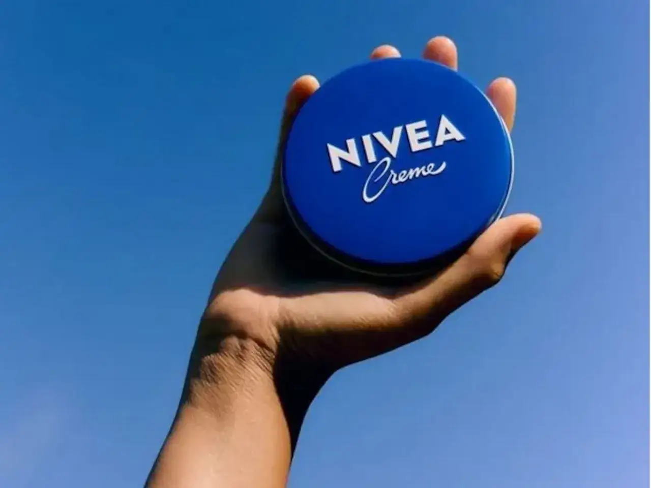Mano sostiene lata azul Nivea Creme. Dicen que la crema Nivea lata azul es mala, pero la imagen solo muestra el producto.