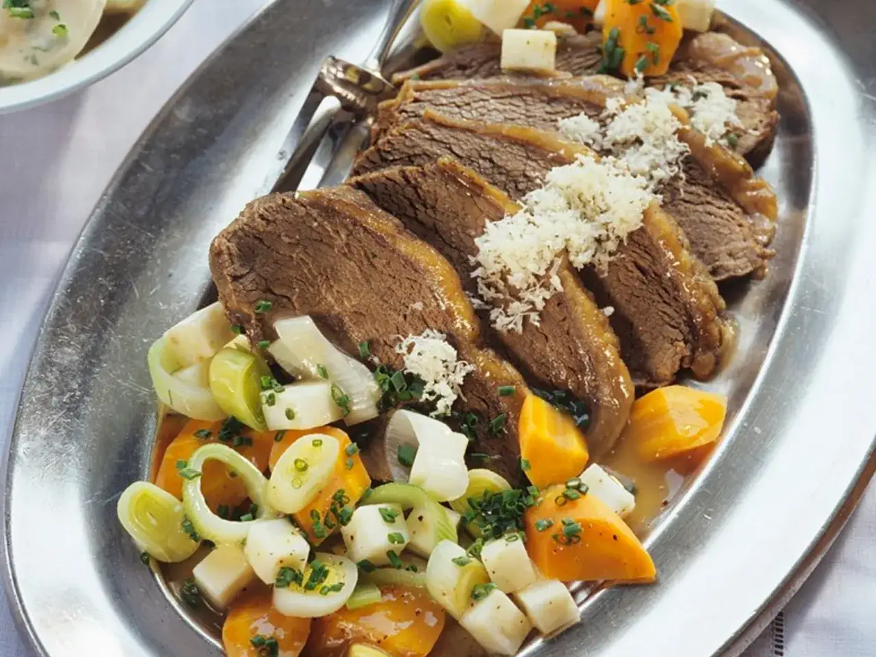 Ein klassisches Tafelspitz Rezept: Zartes Rindfleisch mit Wurzelgemüse und Meerrettich serviert auf einer ovalen Platte.