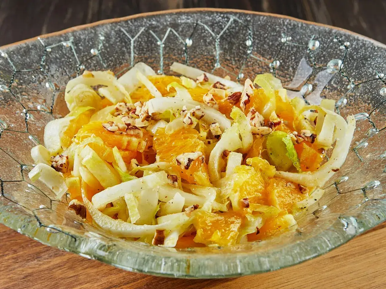 Erfrischender chicoree salat mit Orangenfilets und gehackten N&uuml;ssen in einer dekorativen Glasschale.