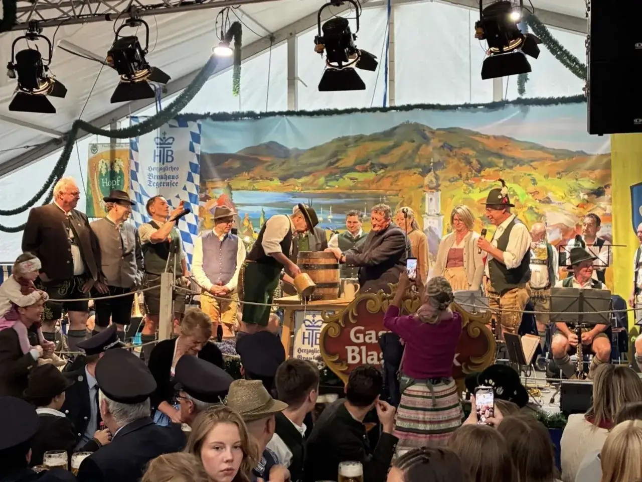 Beim Volksfest Gmund wird ein Bierfass angestochen. Eine Band spielt im Hintergrund, w&auml;hrend G&auml;ste mit Handys filmen.