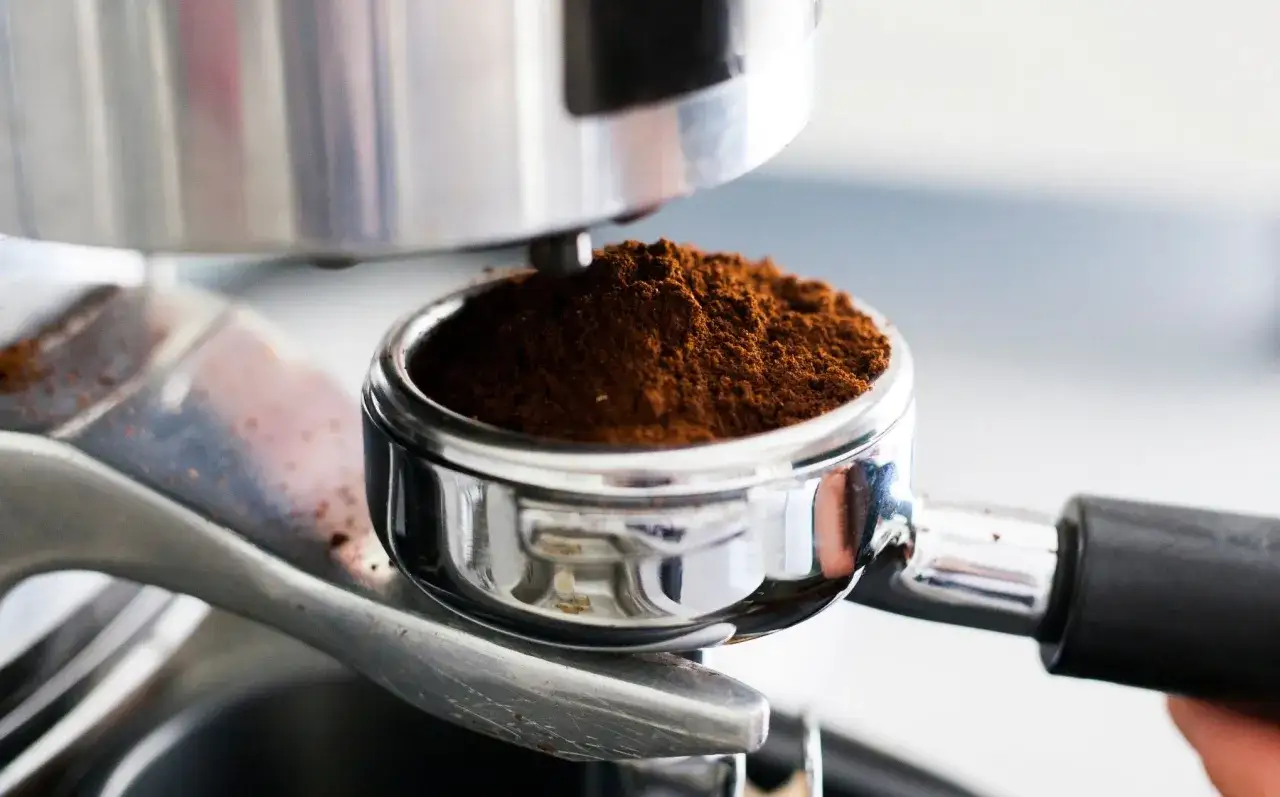 Macinatura caff&egrave; per moka, pronta per un espresso aromatico. Il caff&egrave; macinato riempie il portafiltro cromato.