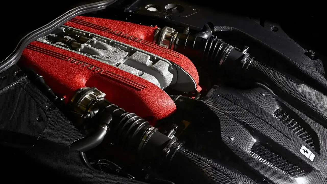 Silnik Ferrari F12 TDF z czerwonymi pokrywami zaworów i elementami z włókna węglowego.