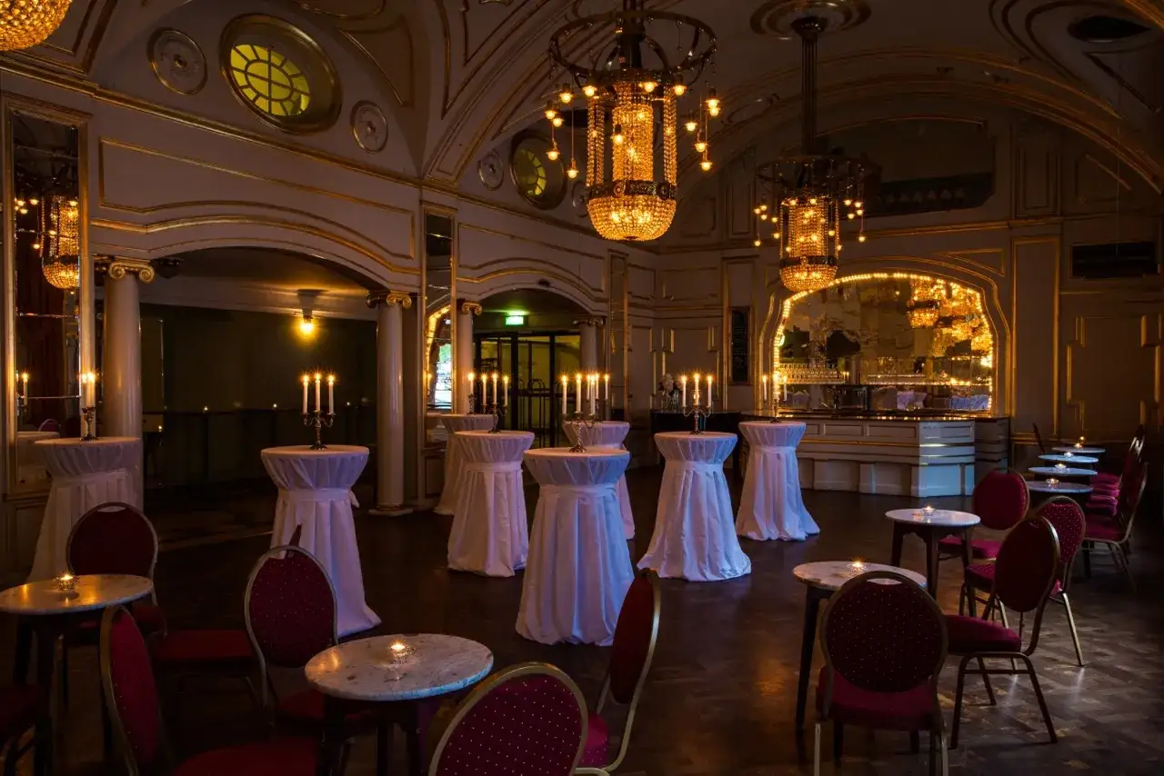 Elegant foajé på Oscars Teatern med dukade ståbord, ljus och lyxiga kristallkronor.