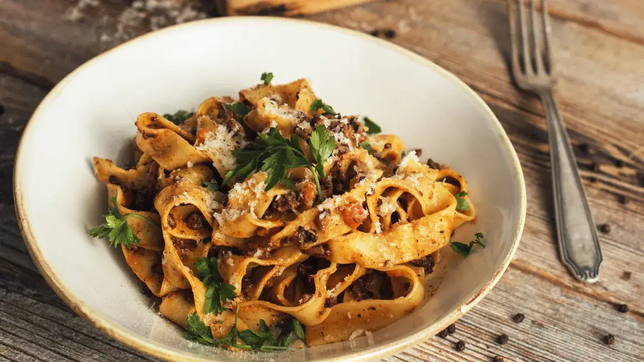 Pappardelle z sosem bolognese, posypane parmezanem i natką pietruszki. Prawdziwy smak Włoch, idealny spaghetti bolognese przepis oryginalny.