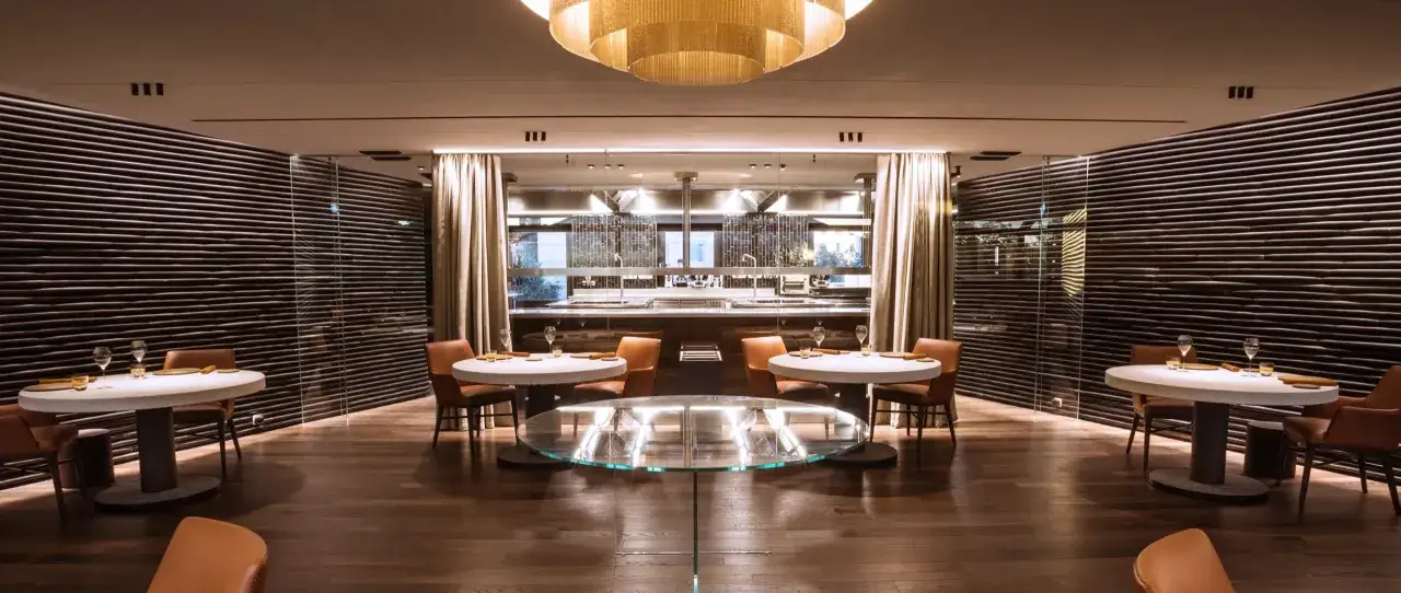 Interni eleganti di ristoranti 2 stelle Michelin Italia, con tavoli apparecchiati e cucina a vista.