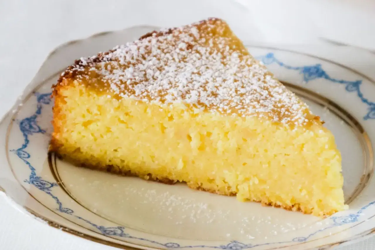 En saftig italiensk mandelkaka med citron, pudrad med florsocker, serveras p&aring; en vacker tallrik.