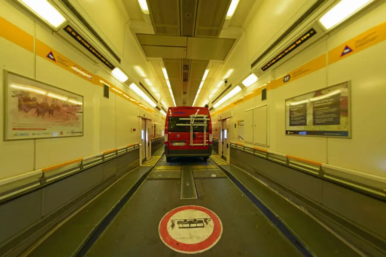 Czerwony kamper wjeżdża do tunelu. Podróż przez eurotunel samochodem to szybki sposób na pokonanie kanału La Manche.