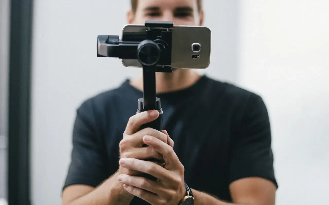 osoba trzymająca aparat fotograficzny i smartfon