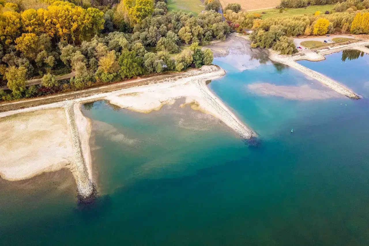 Herbstliche B&auml;ume s&auml;umen die Weser. Ein ruhiger Ort f&uuml;r Angeln, mit sandigen Ufern und klarem Wasser.