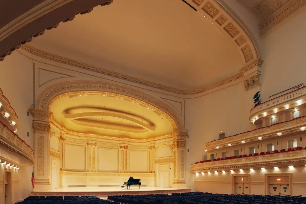 Sc&egrave;ne de concert orn&eacute;e, pr&ecirc;te pour la musique classique moderne. Un piano &agrave; queue noir attend sur la sc&egrave;ne dor&eacute;e, sous des balcons &eacute;l&eacute;gants.