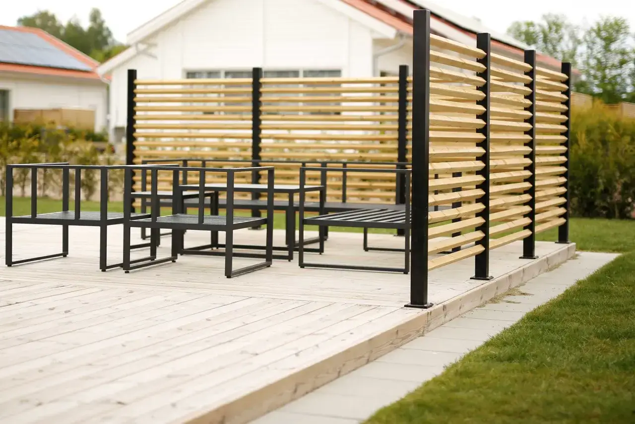En tr&auml;altan med moderna svarta m&ouml;bler och en snygg tr&auml;ribb-sk&auml;rm som skapar ett plank mellan grannar.