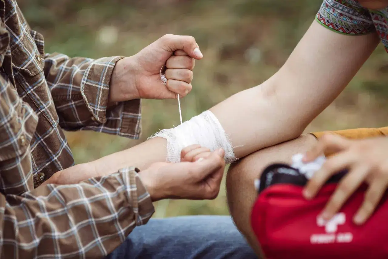 Erste Hilfe bei einem verstauchten Arm: Symptome wie Schwellung und Schmerz werden behandelt, indem der Arm bandagiert wird.