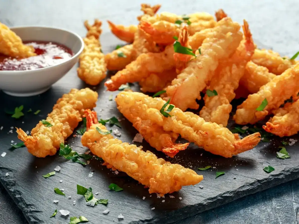 Chrupiące krewetki w cieście, czyli co to jest tempura, podane z sosem.