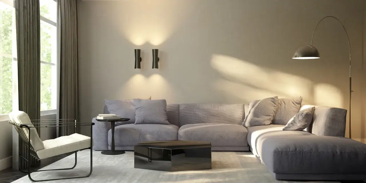 Salon moderne avec canapé gris, fauteuil blanc, table basse miroir et éclairage mural, créant une ambiance chaleureuse sans plafonnier.