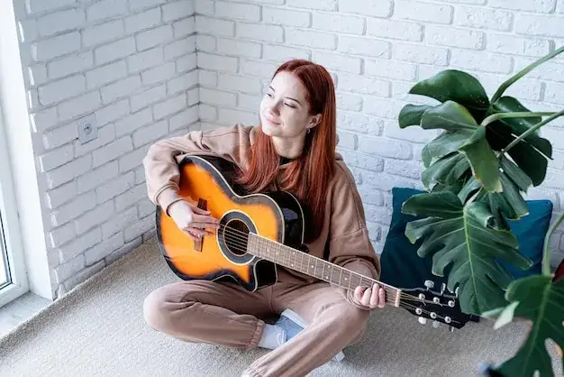 młoda osoba grająca na gitarze akustycznej