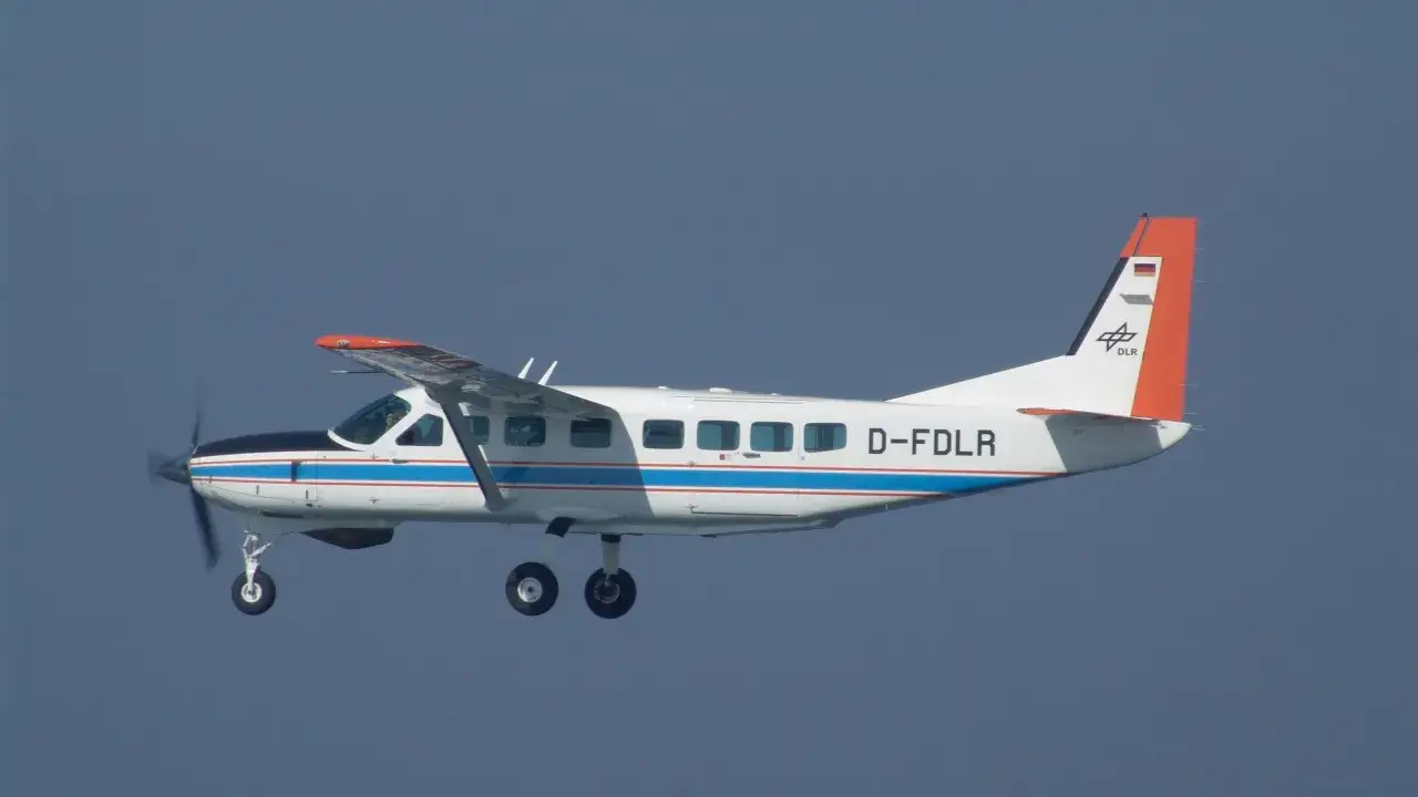 Eine Cessna Grand Caravan mit DLR-Logo fliegt im blauen Himmel.