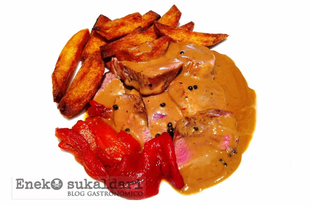 Delicioso solomillo a la pimienta con patatas fritas crujientes y pimientos rojos asados.
