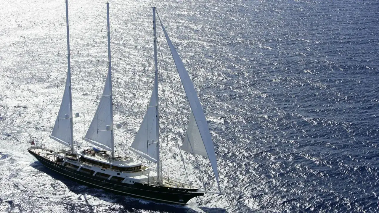 Großes Segelschiff mit weißen Segeln auf glitzerndem Meer. Ein Traum von Luxus und Freiheit, wie ein Schluck pink gin vi.