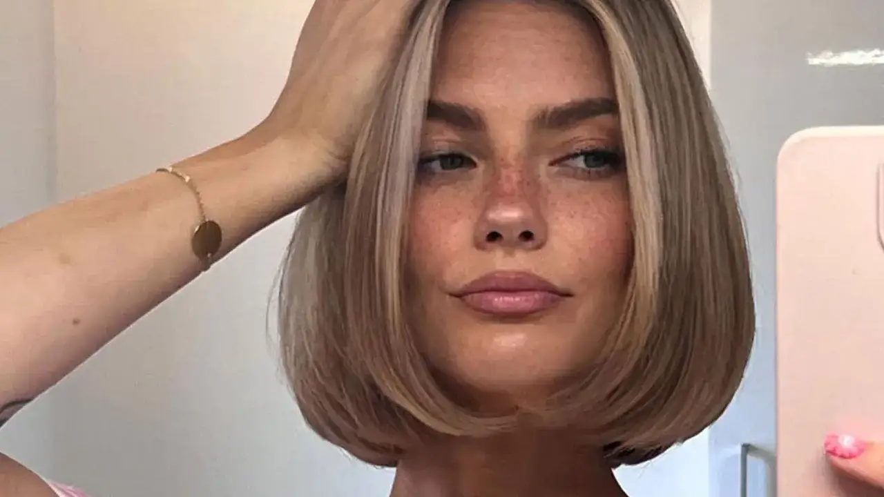 Frau mit kinnlangen Haaren, Sommersprossen und einem goldenen Armband.