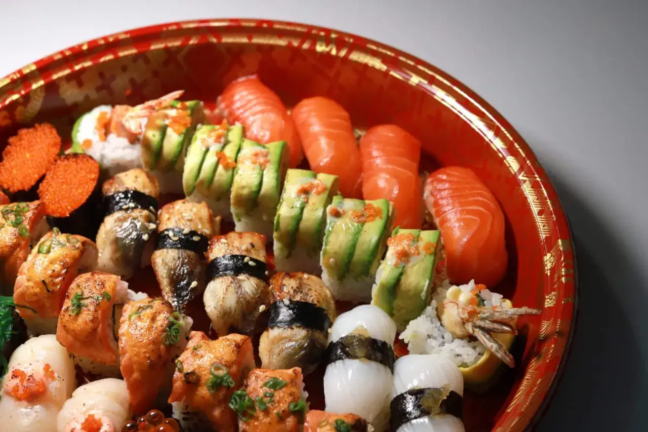 Talerz pełen pysznego sushi: łosoś, awokado, węgorz, krewetki i ikra. Idealne na wspólne jedzenie.
