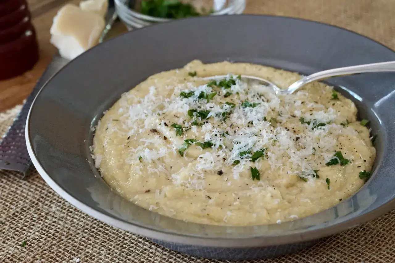 Cremige Polenta, ein italienisches Rezept, garniert mit Parmesan und Petersilie. Perfekt für ein gemütliches Essen.