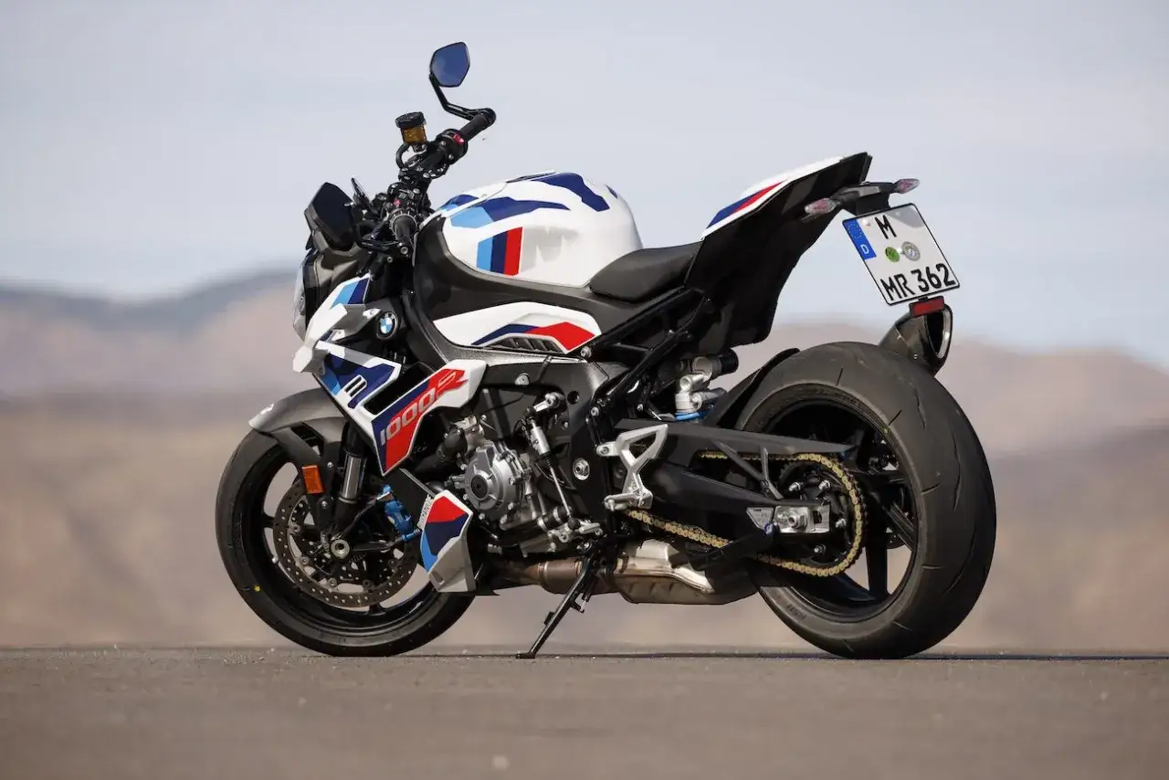 Sportowy motocykl BMW XR w biało-niebiesko-czerwonych barwach M, gotowy do jazdy po pustynnej drodze.