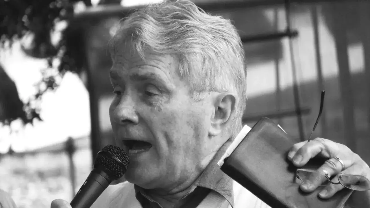 Luis Palau spricht ins Mikrofon, h&auml;lt eine Bibel und eine Brille.
