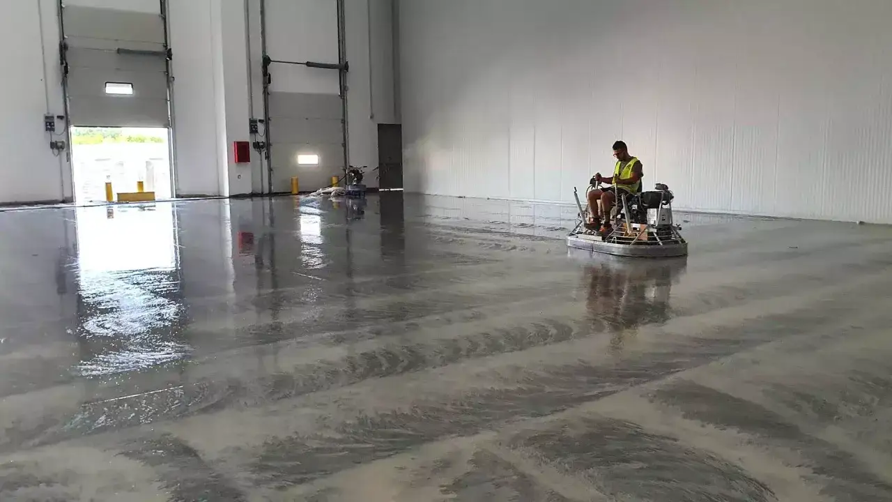 Operaio con elicottero per cemento, mostrando la differenza tra levigatura e lucidatura su un pavimento industriale.