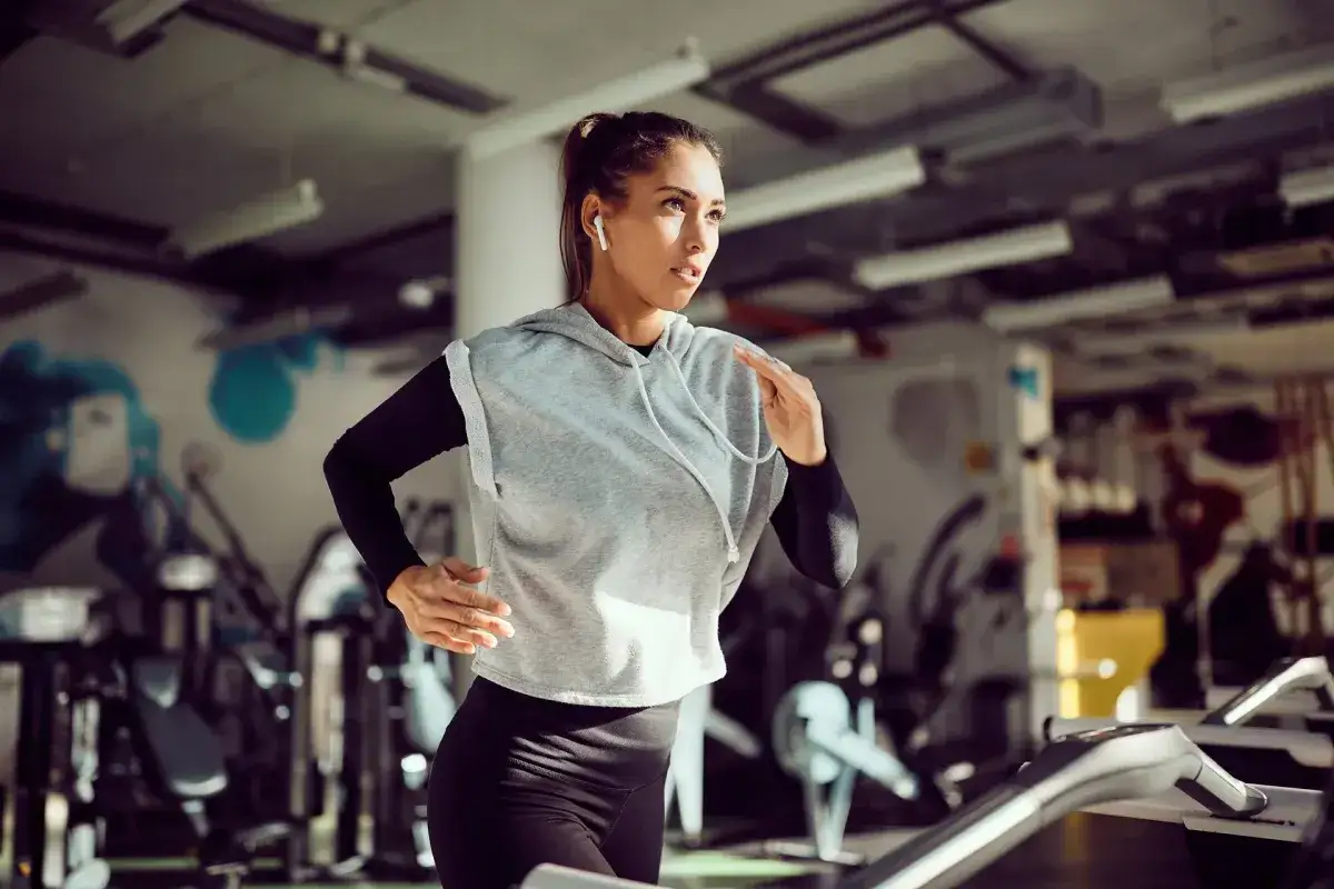 Kvinna springer på löpband i gym, fokuserad på sin träning. Kanske hon använder kreatin för viktnedgång.