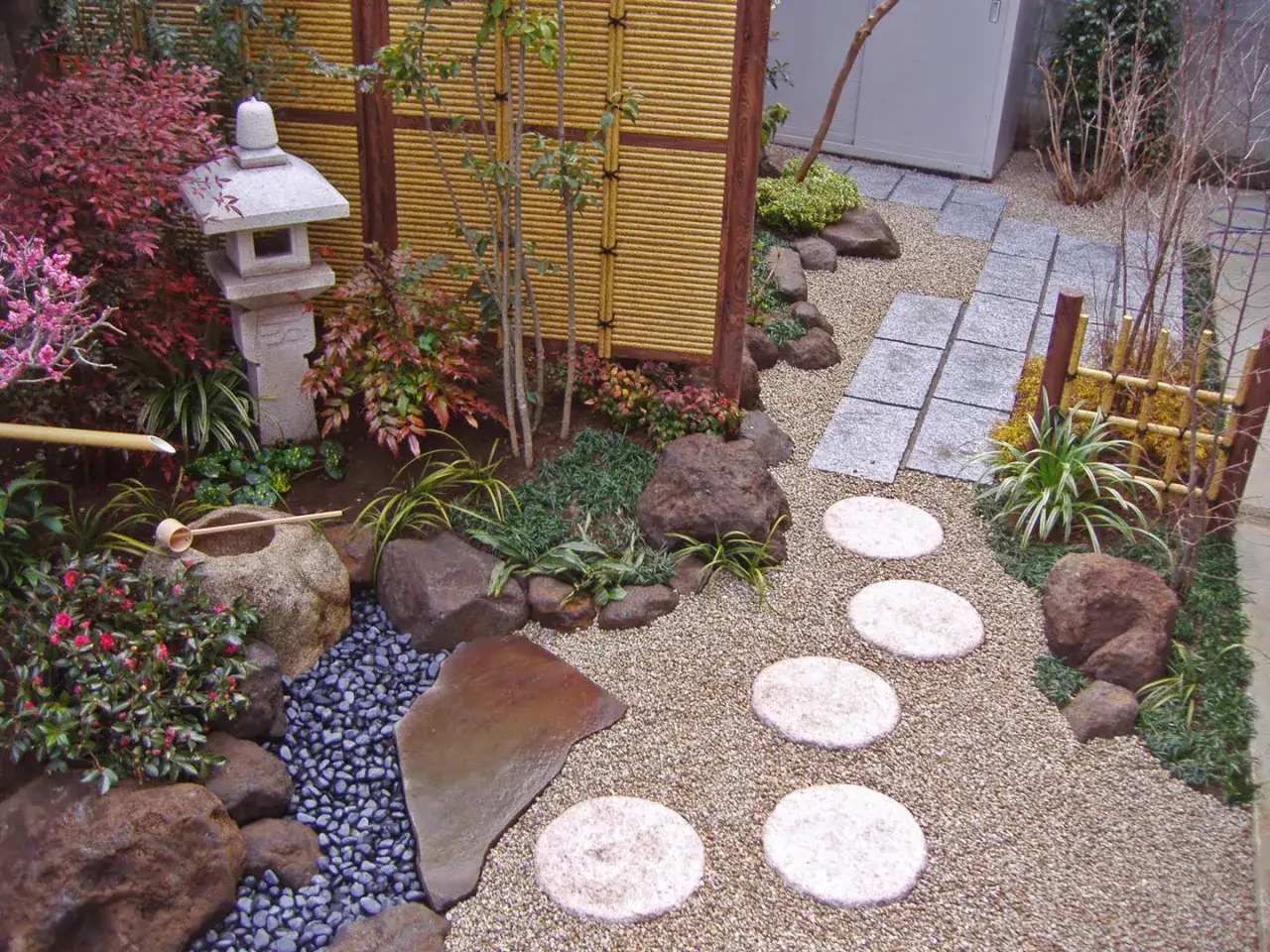 Giardino zen con ghiaia, pietre, lanterne e piante: un esempio di idee giardino senza prato.