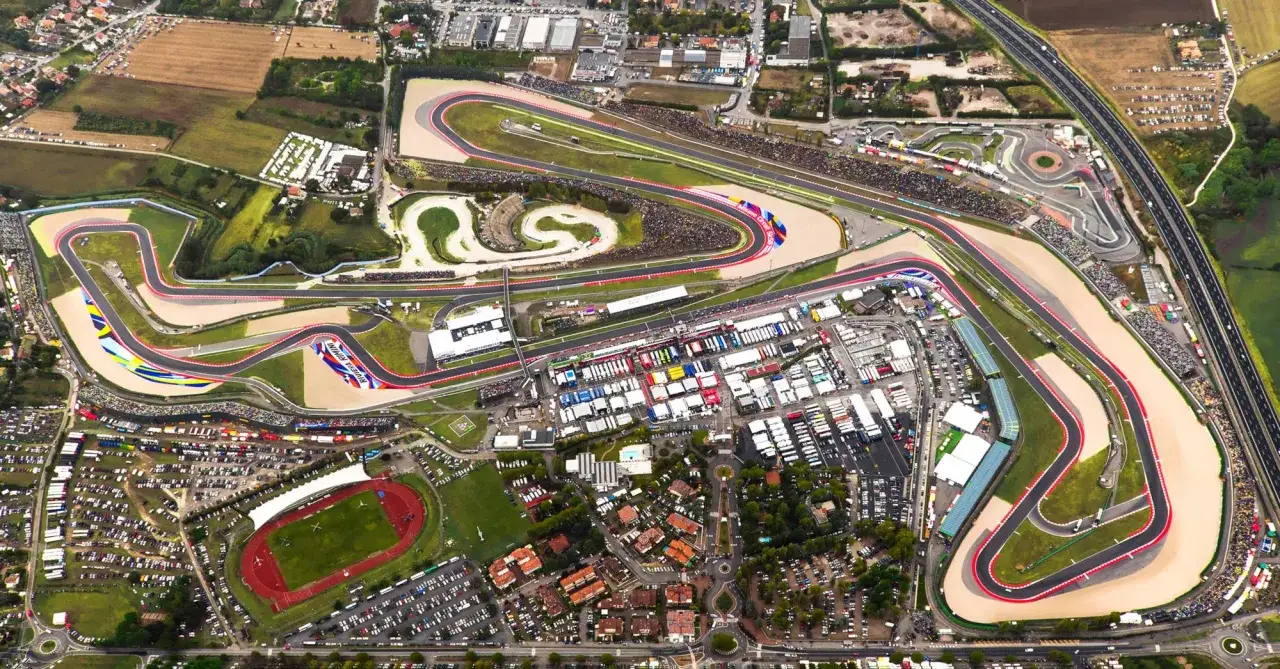 Vista aerea del circuito di Misano, con tribune piene di spettatori e box affollati. Un'intensa giornata di test.