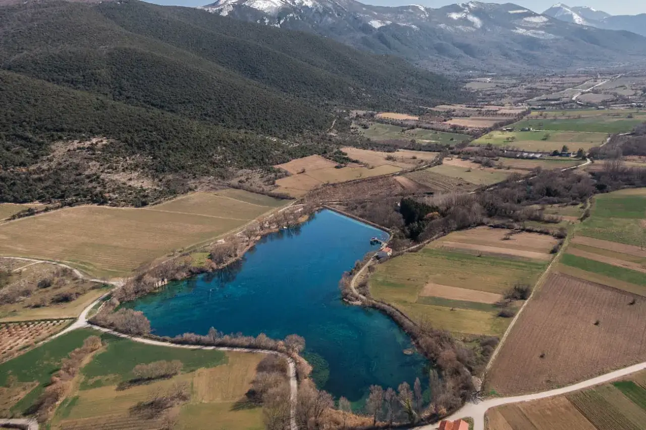 Lago blu cristallino, circondato da campi coltivati e montagne innevate. Un vero e proprio