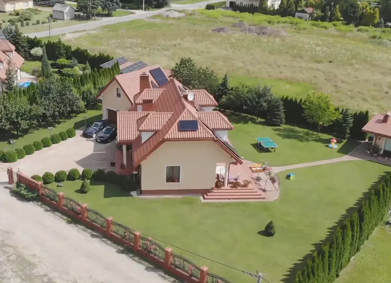 Piękny dom z ogrodem, gdzie mieszka Skolim. Widać panele słoneczne, stół do ping-ponga i plac zabaw.